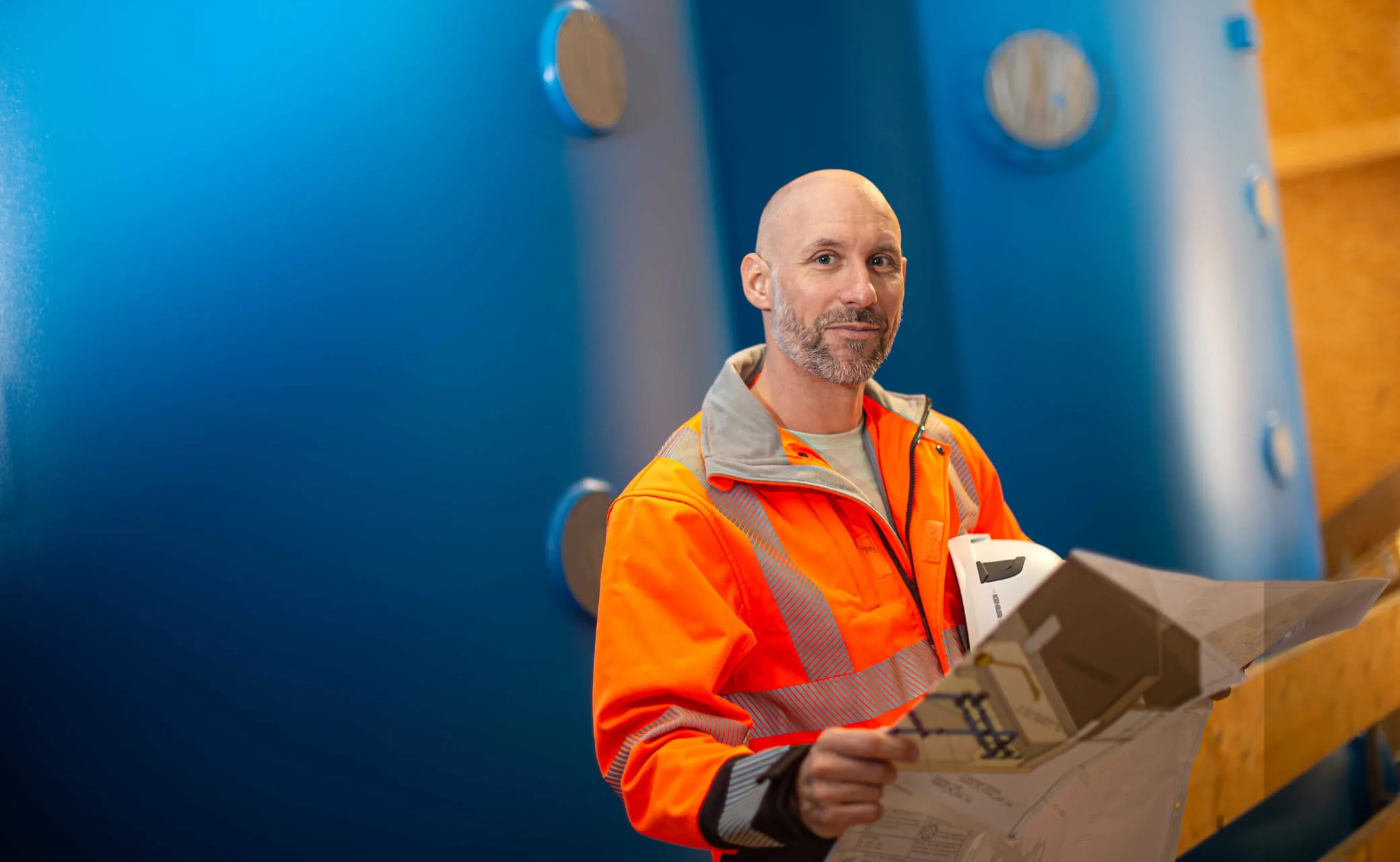 Mitarbeiter mit Warnjacke und Plan in den Händen haltend