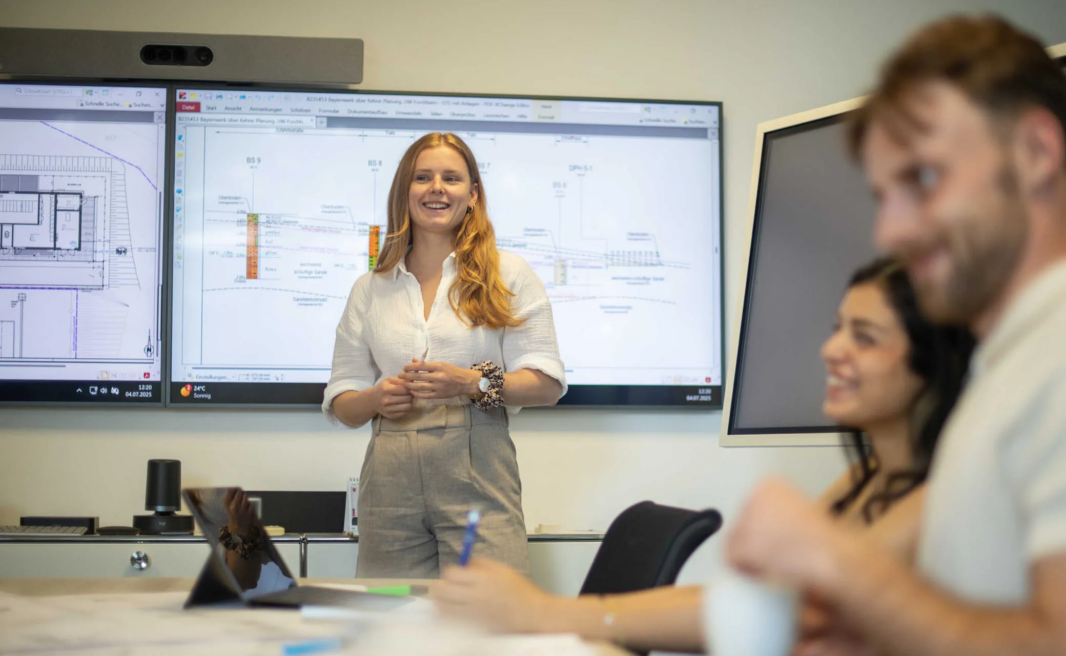 Teambesprechung mit Mitarbeiterin vor Plänen auf Bildschirm